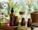 چند شیشه کوچک روغن گیاهی معطر کنار اسطوخودوس، برگ‌های سبز و قطره‌چکان روی میز روشن