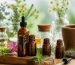 چند شیشه کوچک روغن گیاهی معطر کنار اسطوخودوس، برگ‌های سبز و قطره‌چکان روی میز روشن