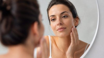 نمای نزدیک از گونه زنی جوان با پوست طبیعی و شفاف در نور ملایم روز