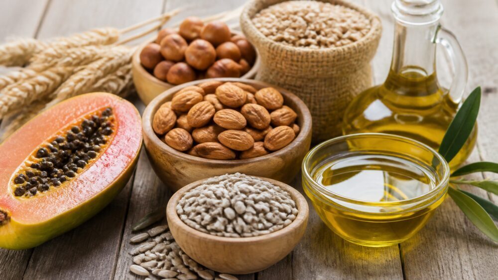 کاسه ای از بادام و تخمه آفتابگردان در کنار بطری روغن زیتون و آووکادو