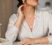 نمای نزدیک از زنی با گوشواره‌های طلایی ظریف و گردنبند لایه‌ای مینیمال در نور طبیعی
