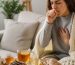 فنجان دمنوش گرم در کنار ریشه شیرین‌بیان، حبه‌های سیر و عسل روی میز چوبی