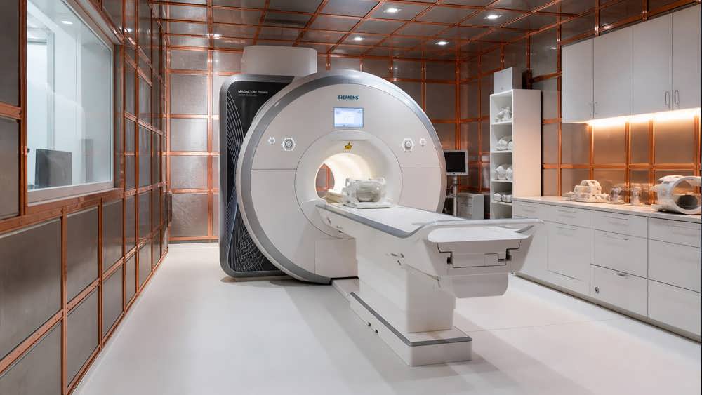 یک دستگاه مدرن ام آرآی (MRI) در داخل یک اتاق کلینیک که دیوارهای آن با شبکه های فلزی برای شیلد امواج پوشانده شده است.