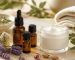 شیشه‌های روغن ضروری، کاسه کرم مرطوب‌کننده و گل‌های اسطوخودوس روی میز روشن