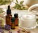 شیشه‌های روغن ضروری، کاسه کرم مرطوب‌کننده و گل‌های اسطوخودوس روی میز روشن