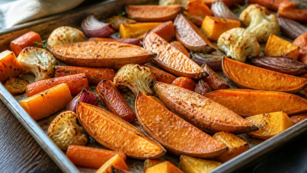 برش های شقاقل و هویج برشته با روغن زیتون روی سینی فر، همراه با پیاز و گل کلم