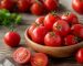 چند گوجه‌فرنگی تازه و برش‌خورده روی تخته چوبی در نور طبیعی آشپزخانه