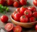 چند گوجه‌فرنگی تازه و برش‌خورده روی تخته چوبی در نور طبیعی آشپزخانه
