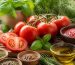 گوجه‌فرنگی‌های تازه کنار ریحان، آویشن، رزماری، سیر و ادویه‌های رنگارنگ روی میز آشپزخانه