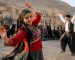 گروهی از مردم با لباس‌های محلی در حال اجرای موسیقی و رقص سنتی در فضای باز