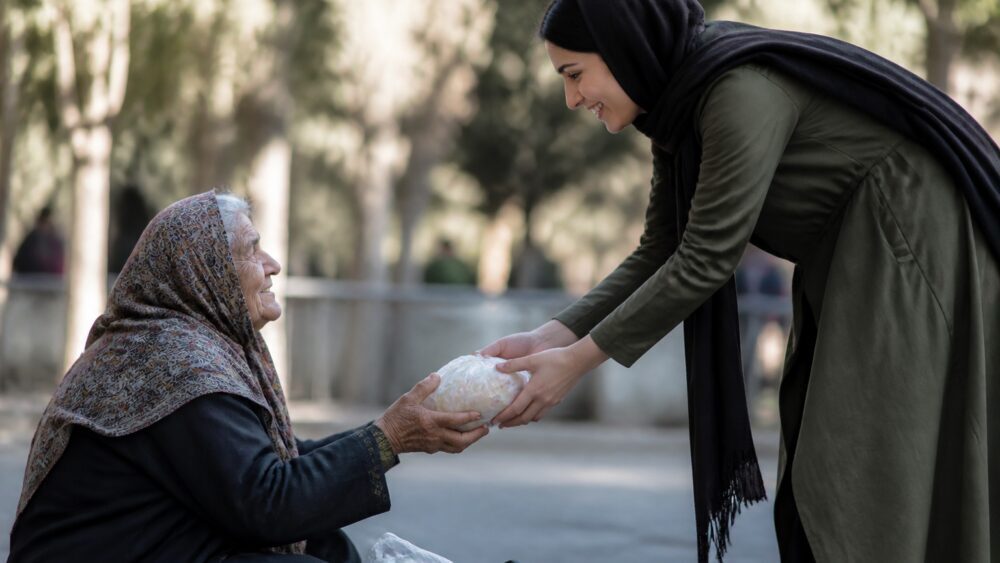 زنی جوان با چهره ای آرام دست دوست اندوهگین خود را در فضای سبز شهری گرفته است