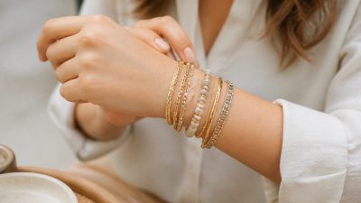 مچ دست زن با چند دستبند طلایی و نقره‌ای لایه‌لایه در نور طبیعی